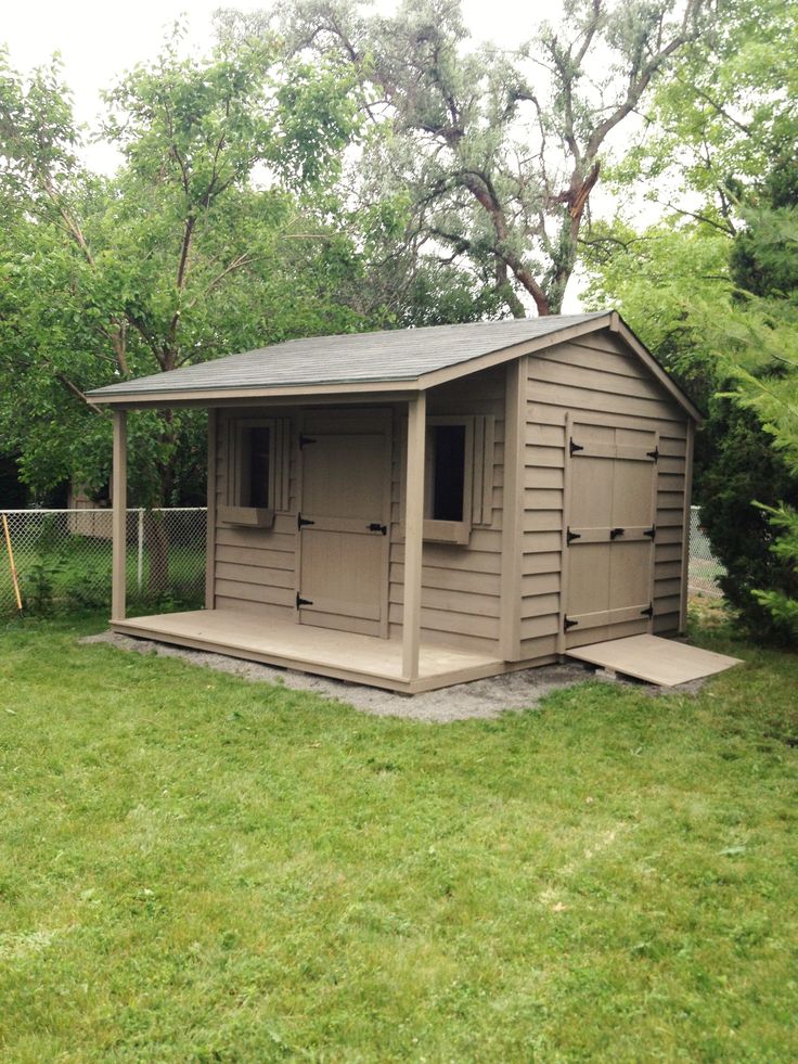 a small shed sitting on top of a lush green field next to a fenced in area