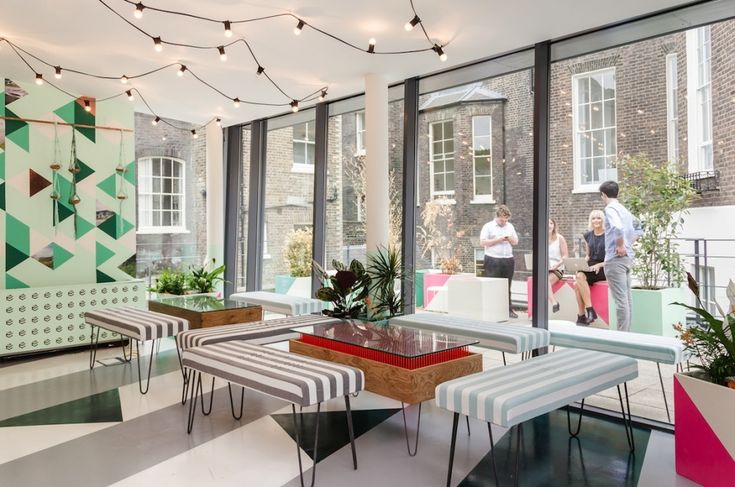 a room filled with lots of tables and chairs in front of large windows covered by string lights