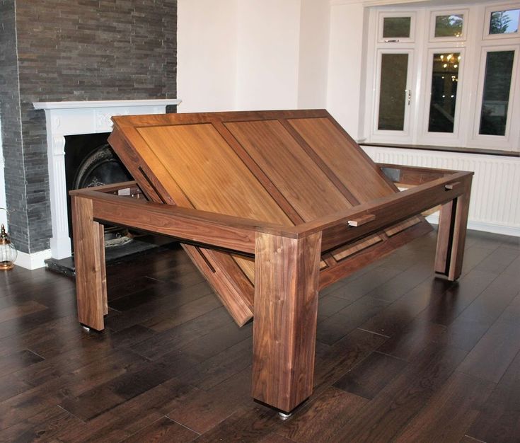 a wooden table sitting on top of a hard wood floor next to a fire place