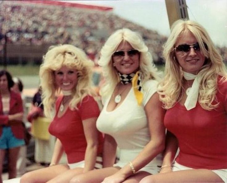 three women dressed in red and white posing for a photo at a football game with fans