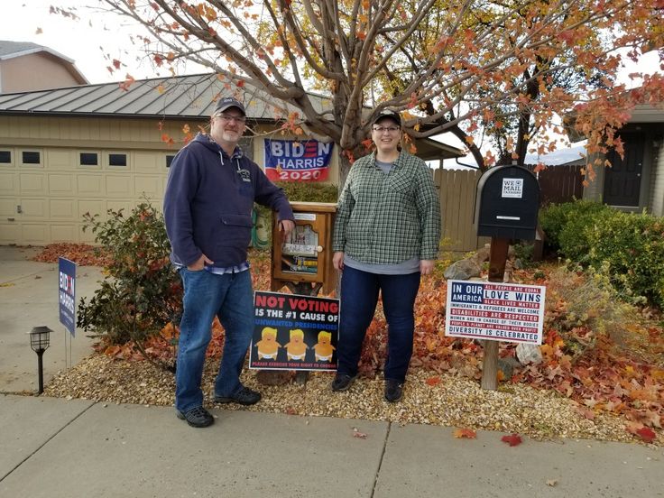 two men standing in front of a yard sale sign on the side of a road