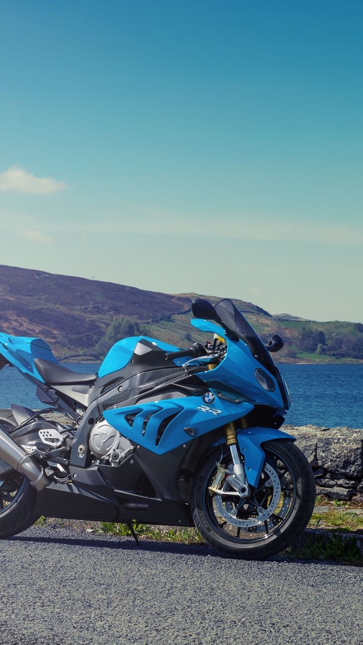 a blue motorcycle parked next to the ocean