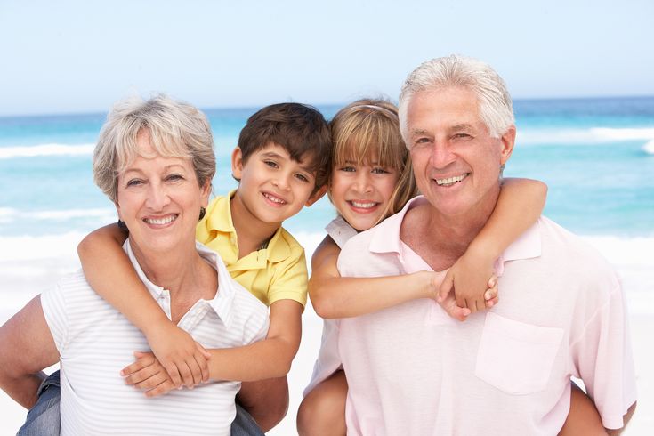 an older man, woman and two children on the beach