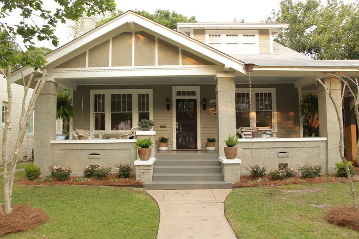 a small house with two front porches and plants in pots on the steps leading up to it