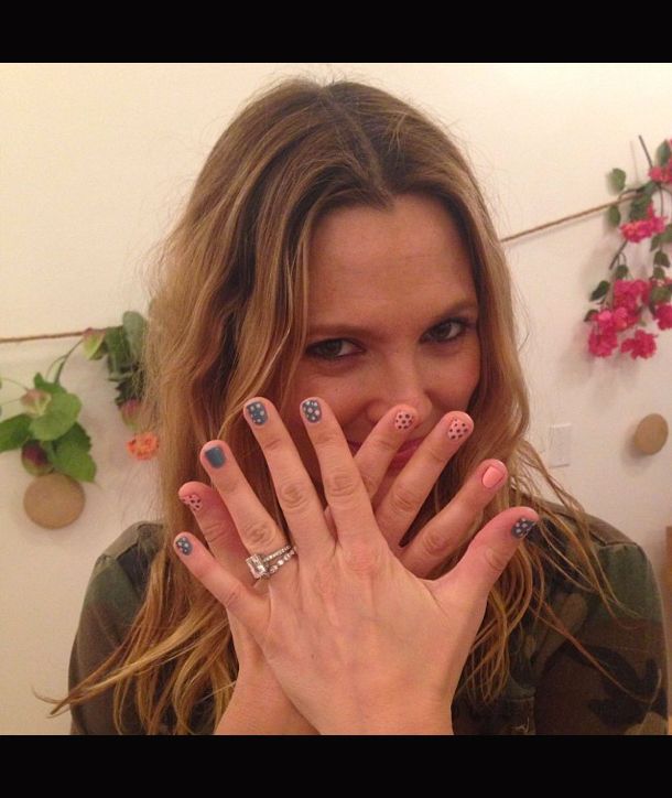 a woman holding her hands up to her face with polka dots on the nail polish