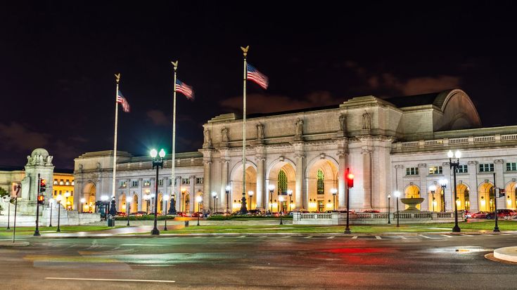 the building is lit up at night and has many flags flying in front of it