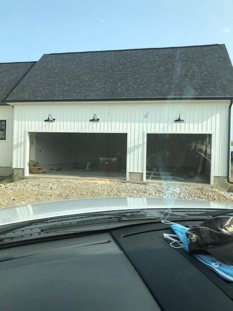 a car is parked in front of a white building with two garages on the other side