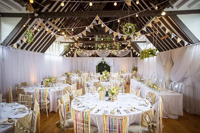 a banquet hall with tables and chairs covered in white linens, decorated with colorful ribbons