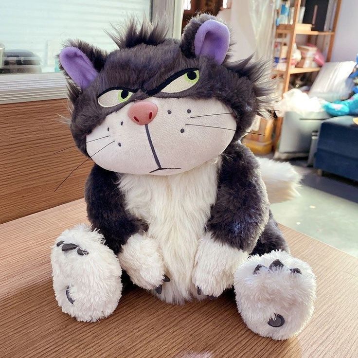 a stuffed cat sitting on top of a wooden table