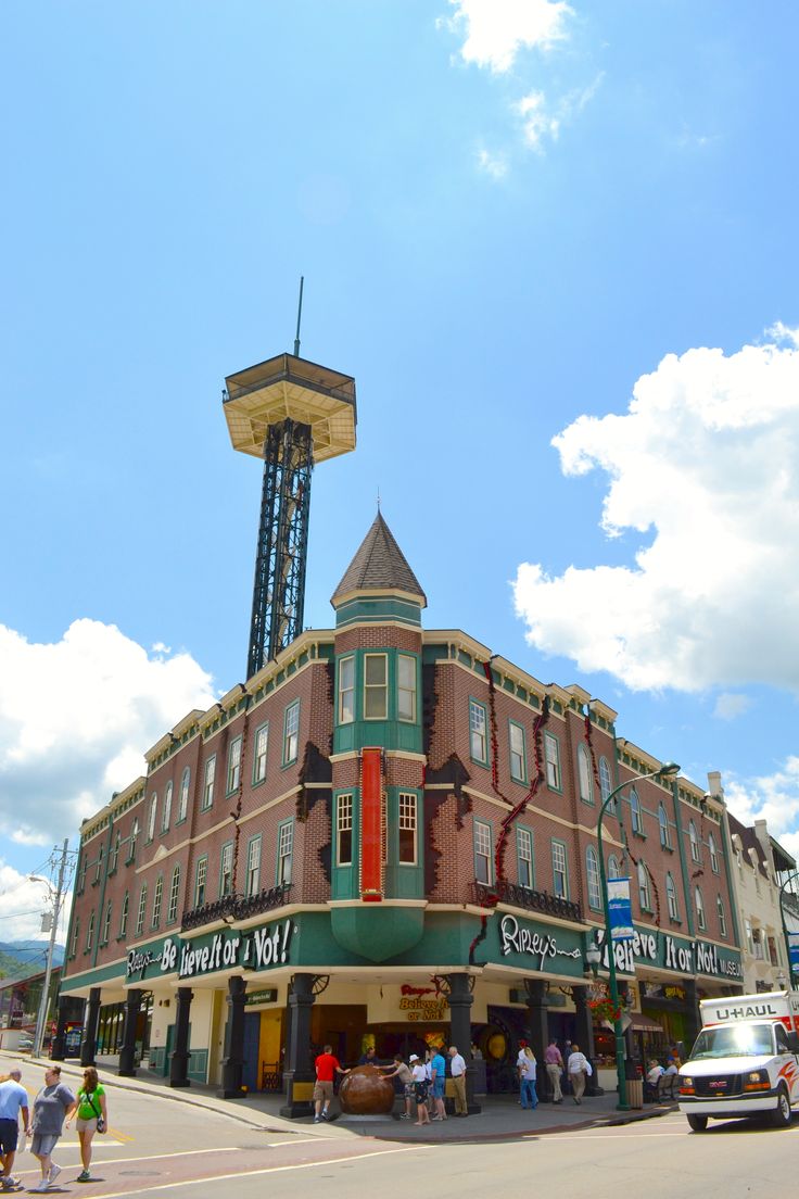 people are walking around in front of a building with a water tower on the top