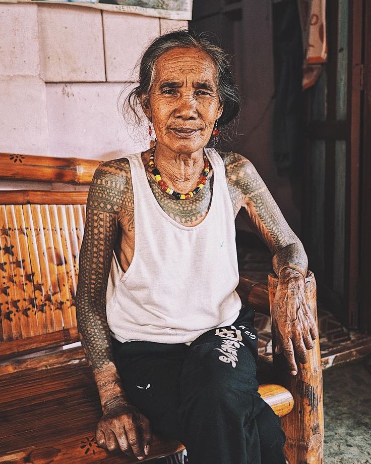 an old woman with tattoos sitting on a bench