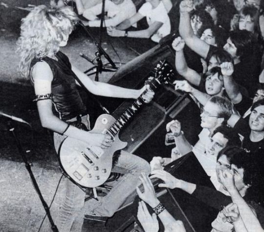 a woman playing guitar in front of a group of people