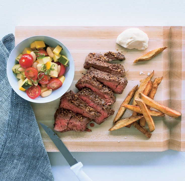 steak, salad and french fries on a cutting board