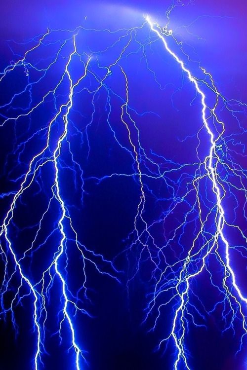 lightning strikes in the night sky with blue and purple lighting on it's sides