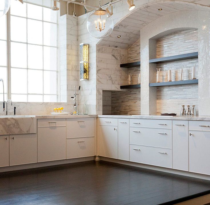 an empty kitchen with white cabinets and marble counter tops, in front of a large window