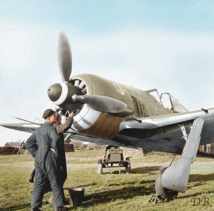 two men standing next to an old airplane