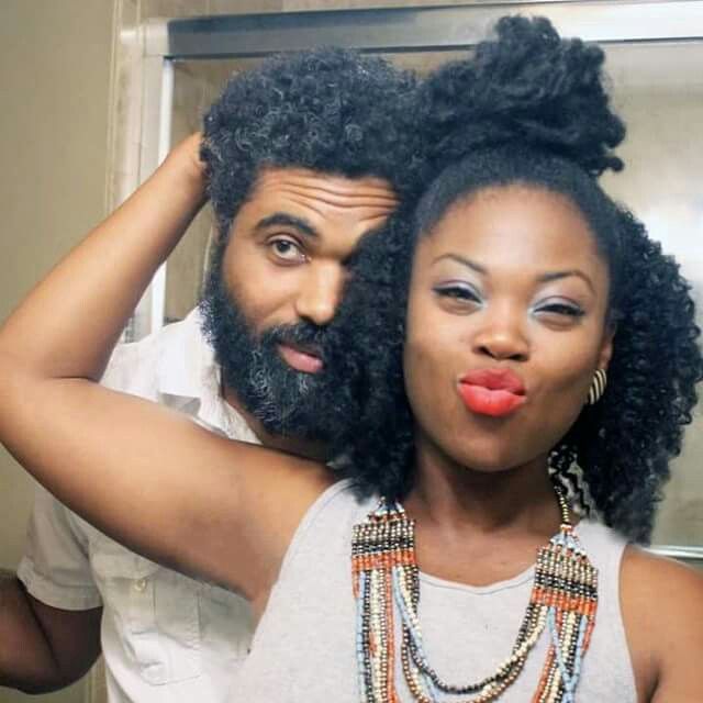 a man and woman with afros are making faces in front of a mirror while brushing their hair