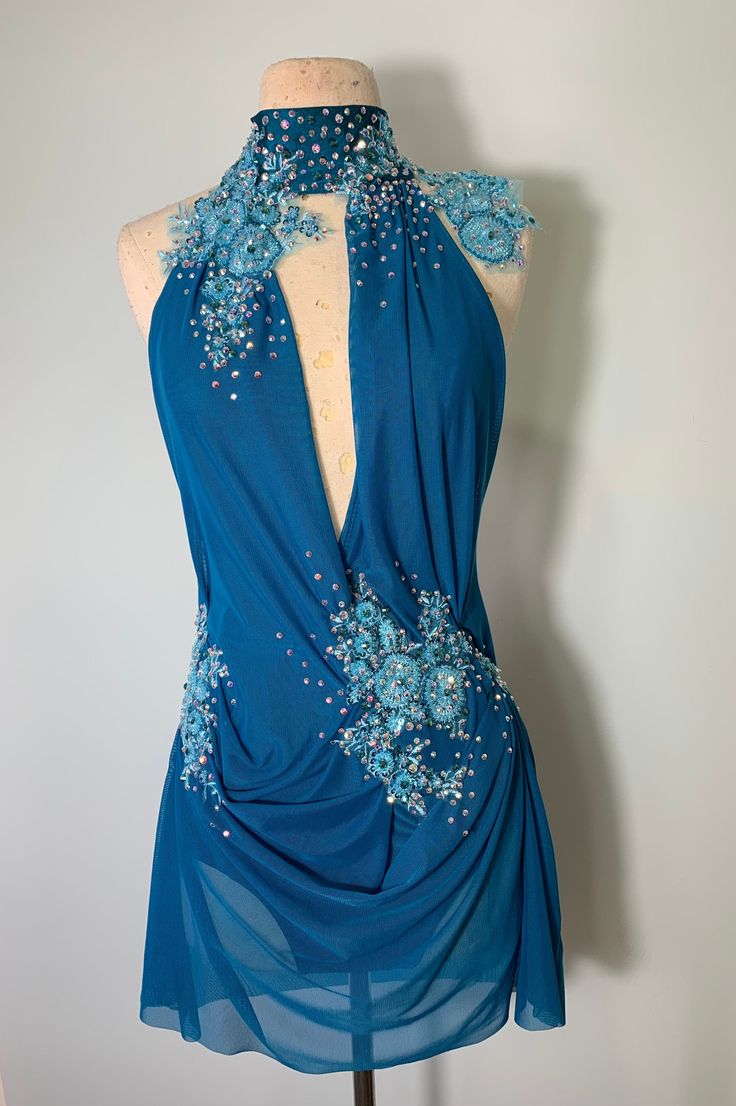 a dress on a mannequin with blue flowers and beads in the neckline