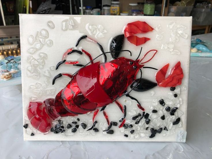 a red and black glass art piece sitting on top of a white table next to other items