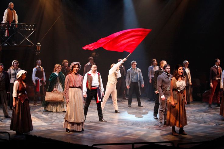 a group of people standing on top of a stage with a red flag in the air