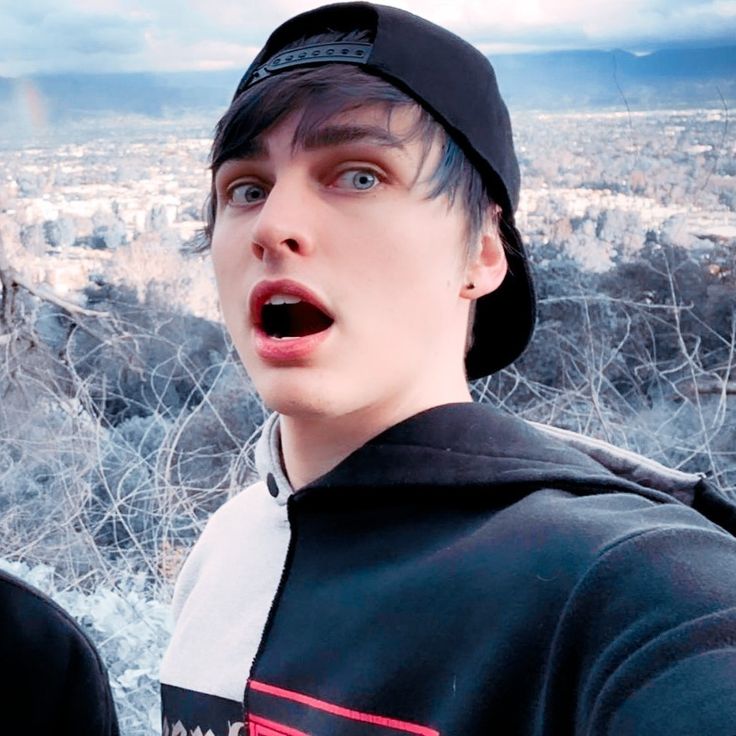 a young man making a surprised face while standing in front of a cityscape