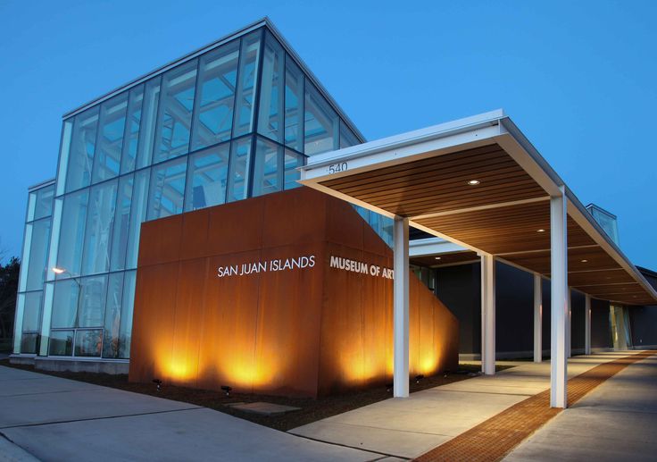 the entrance to an office building lit up at night with lights shining on the outside