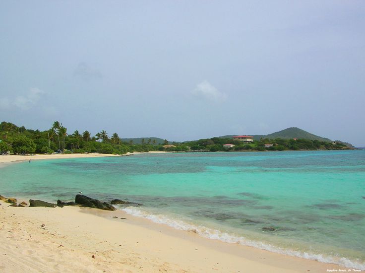 an empty beach with clear blue water and palm trees