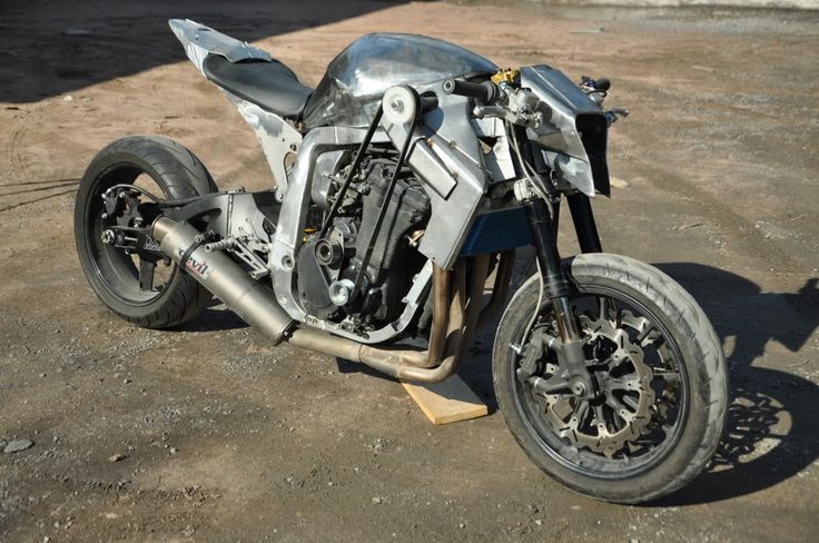 a silver motorcycle parked on top of a parking lot next to a fence and building