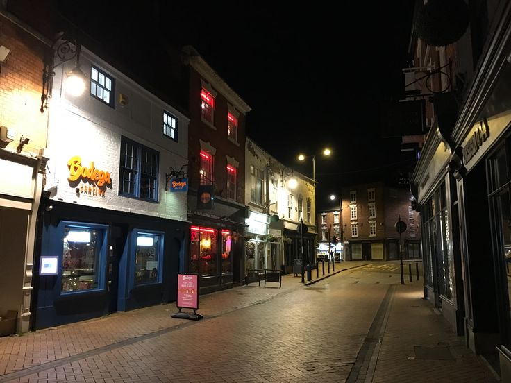 an empty city street at night with buildings lit up