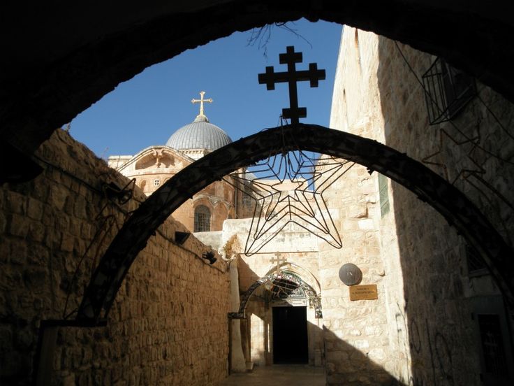 an archway leading to a church with a cross hanging from it's ceiling and another building in the background