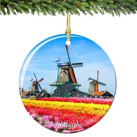 a christmas ornament hanging on a tree with flowers and windmills in the background