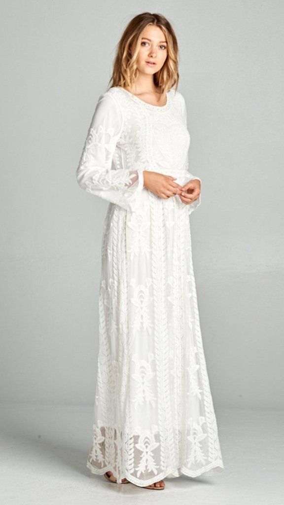 a woman is wearing a white dress with long sleeves and a lace pattern on the bottom