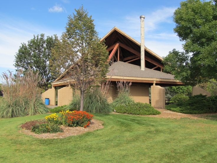 a house with a flower bed in front of it and trees around the yard area