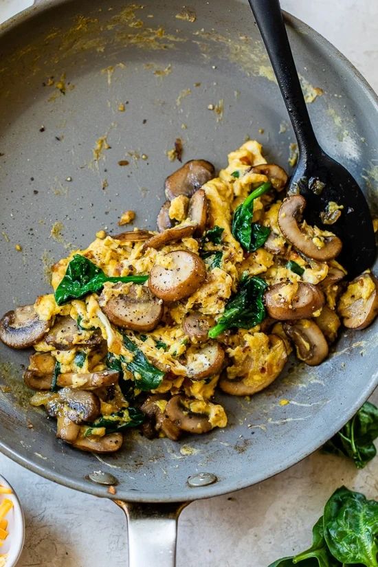 scrambled eggs with mushrooms and spinach in a skillet