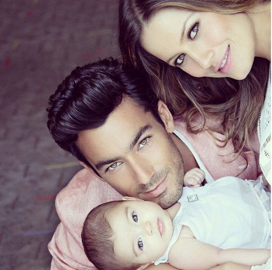 a man and woman holding a baby while posing for a photo with the child on her lap