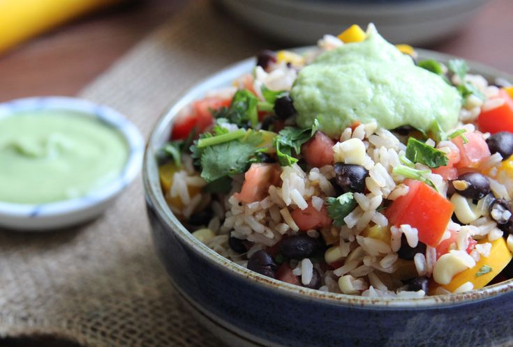 a bowl filled with rice, beans and guacamole on top of a table