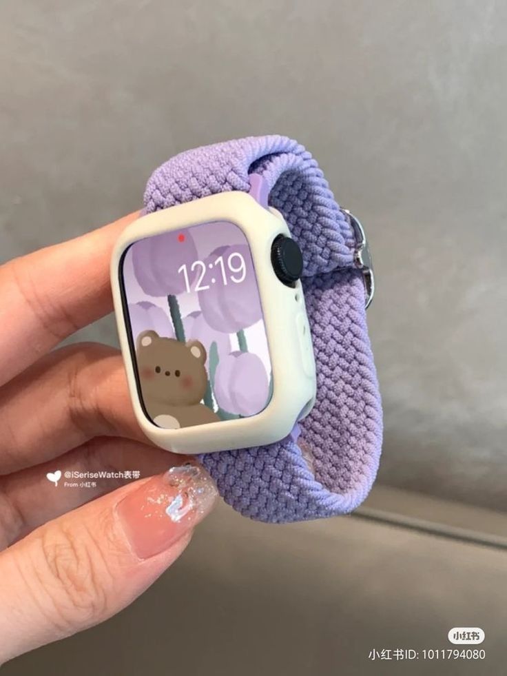 a person holding an electronic watch with a bear on it's face and purple band