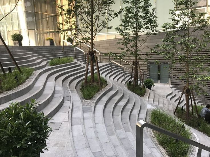 an outdoor area with steps and trees in the center, surrounded by greenery on both sides