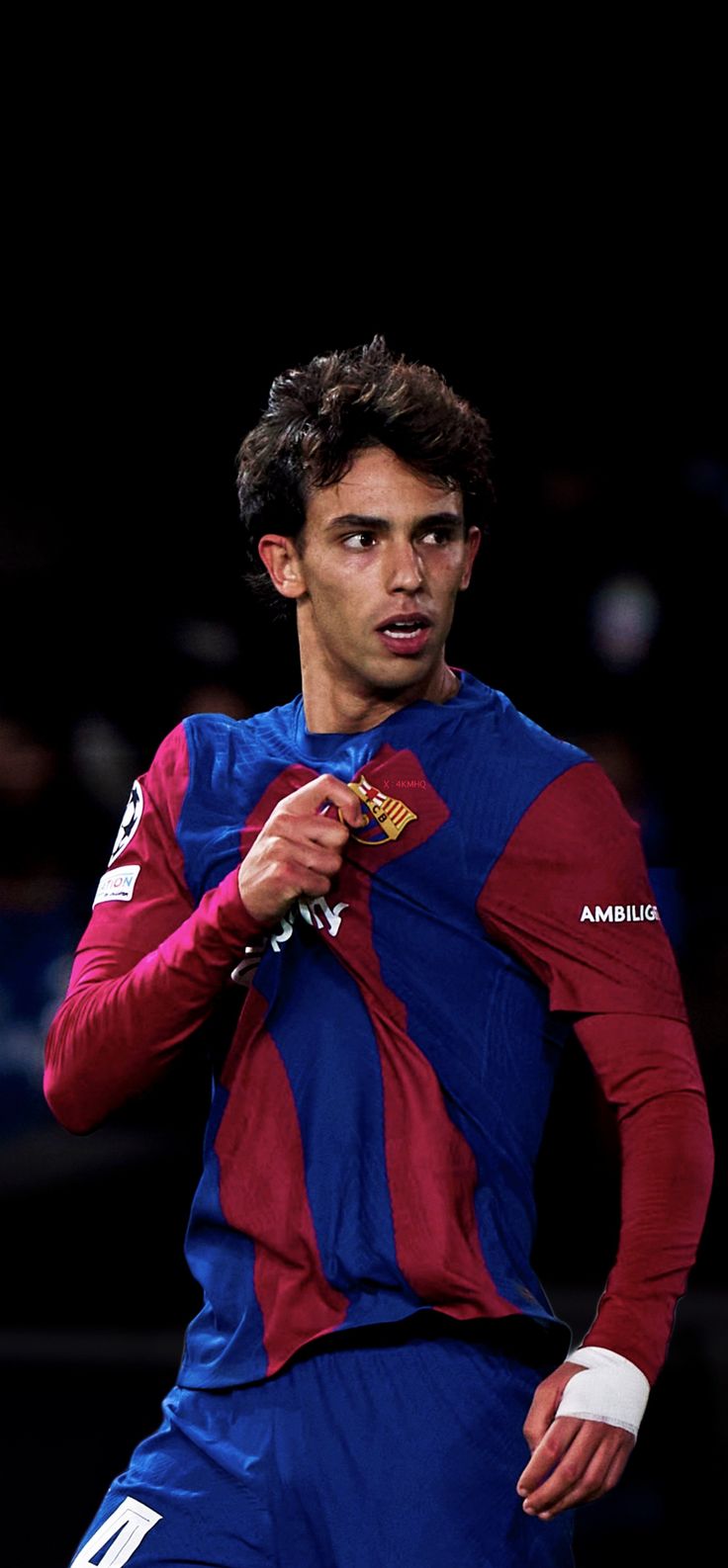 a soccer player in blue and red uniform holding a ball with his right hand as he prepares to kick the ball