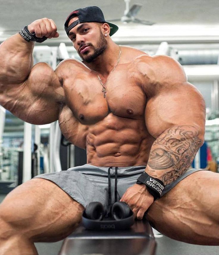 a man sitting on top of a bench flexing his muscles