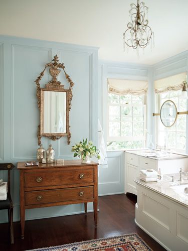 a bathroom with blue walls and wood flooring has a chandelier hanging from the ceiling