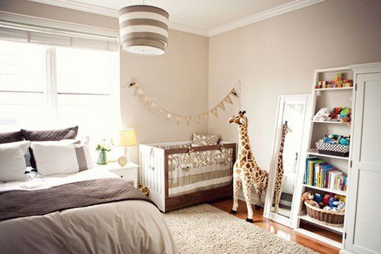 a baby's room with a bed, bookcases and a stuffed giraffe