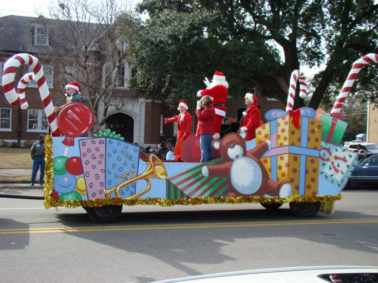 a parade float with people dressed as santa clause riding in the back