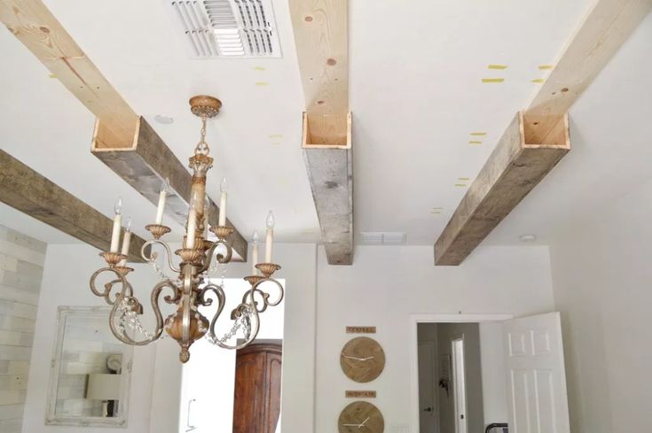 a chandelier hanging from the ceiling in a room with white walls and wood beams