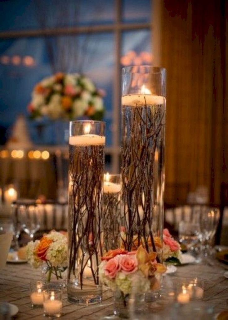 two tall vases filled with flowers and candles on top of a dining room table