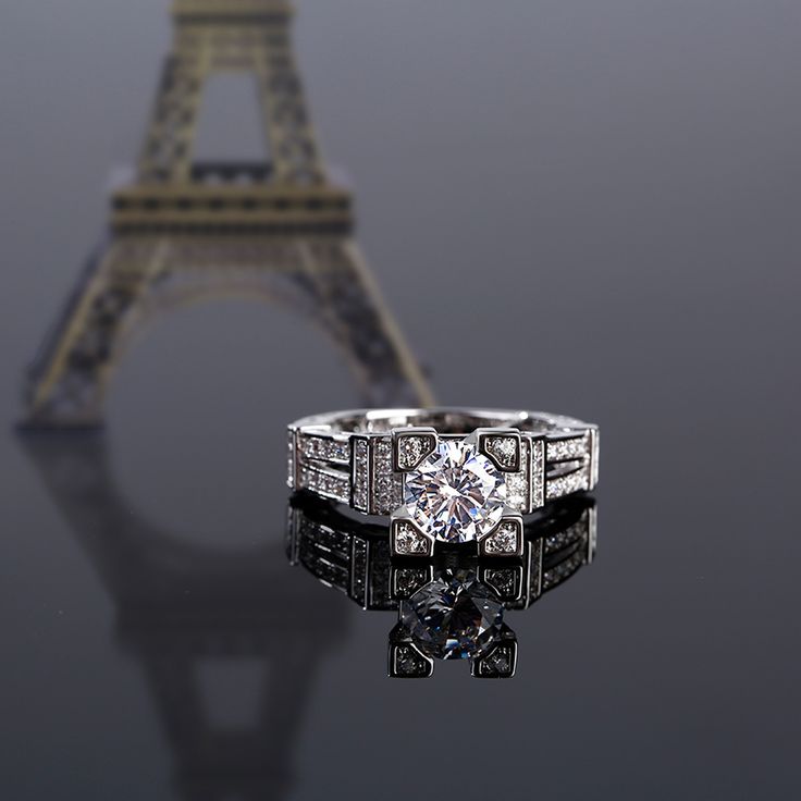 The Eiffel Tower - one of the world's most recognizable landmarks. Inspired by the Eiffel Tower, this ring perfectly demonstrates the structure and beauty of the tower. Crafted in sterling silver, this dazzling design showcases a round cut center stone wrapped in four smaller round stones. Along the shank, several stones complete the design of tower. The start of something beautiful, this glittering ring is sure to please.Carat Weight: 2.5 ctStone Size: 7 mmStone Type: Jeulia® StoneNumber of Stones: 1 Stone Color: Diamond WhiteStone Shape: RoundCarat Weight: 0.818 ctStone Size: 1,0.9,1.5 mmStone Type: Jeulia® StoneNumber of Stones: 74 Stone Color: Diamond WhiteStone Shape: RoundWeight: 5.43 gWidth: 9 mmHeight: 27.7 mmThickness: 3.2 mmMaterial: 925 SilverPlating Color: Silver Luxury Silver Diamond Ring Channel Set, Luxury Silver Channel Set Jewelry, Luxury Sterling Silver Channel Set Diamond Ring, Luxury Sterling Silver Diamond Ring Channel Set, Luxury Channel Set Diamond Ring In Sterling Silver, Luxury Silver Diamond Ring With Round Band, Luxury Platinum Jewelry With Channel Set, Luxury Platinum Channel Set Jewelry, Luxury White Gold Crystal Ring With Brilliant Cut