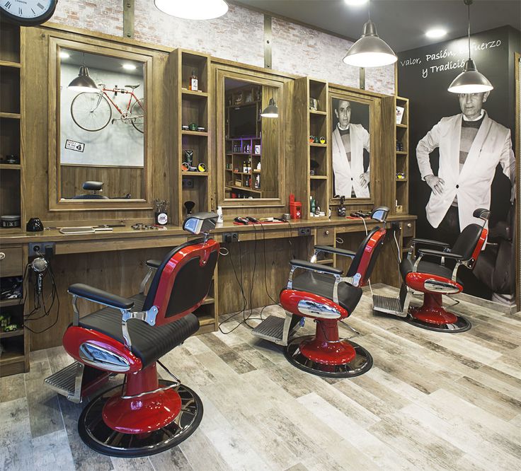 a barber shop with two red chairs in front of the counter and a clock on the wall