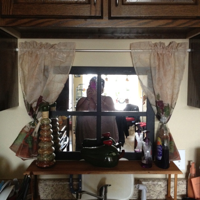 a woman standing in front of a kitchen window next to a sink and counter top