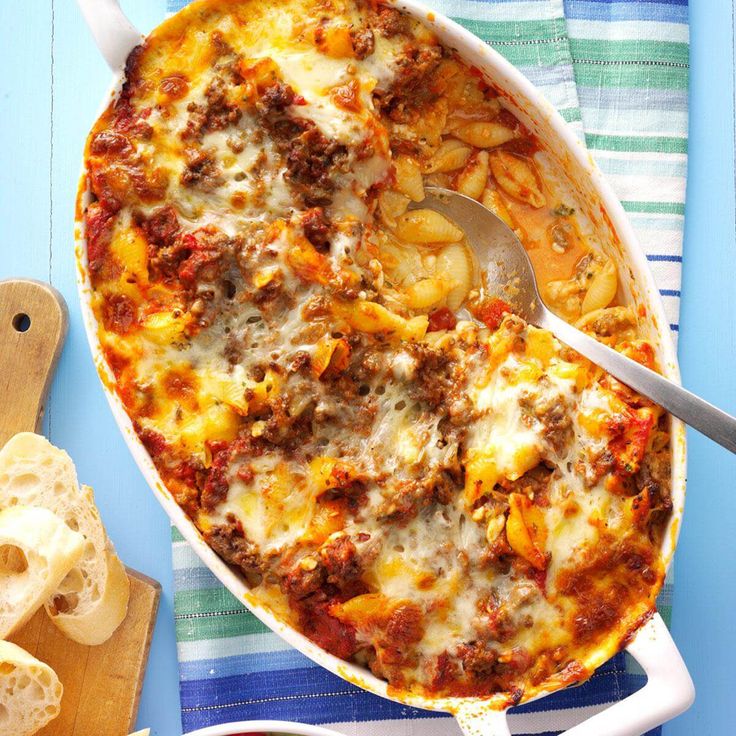 a casserole dish with meat, cheese and bread on a blue tablecloth