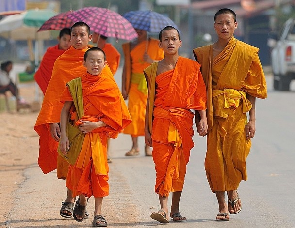 several people in orange robes walking down the street